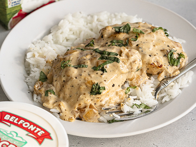 Creamy sour cream and onion chicken served over white rice, garnished with fresh herbs, creates a hearty and savory meal.